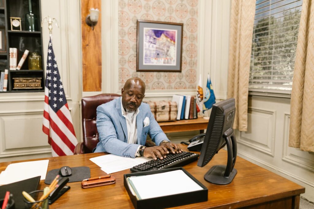 A lawyer in a suit working at his desk in an office with an American flag.