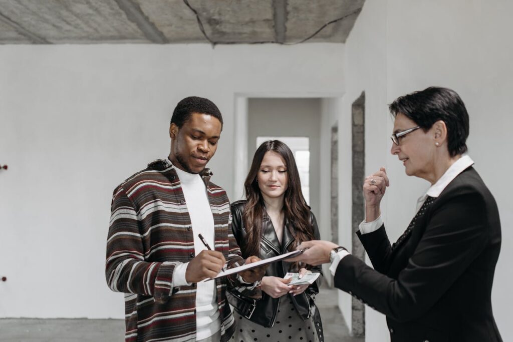 A diverse couple signing documents with a realtor in a new home setting.